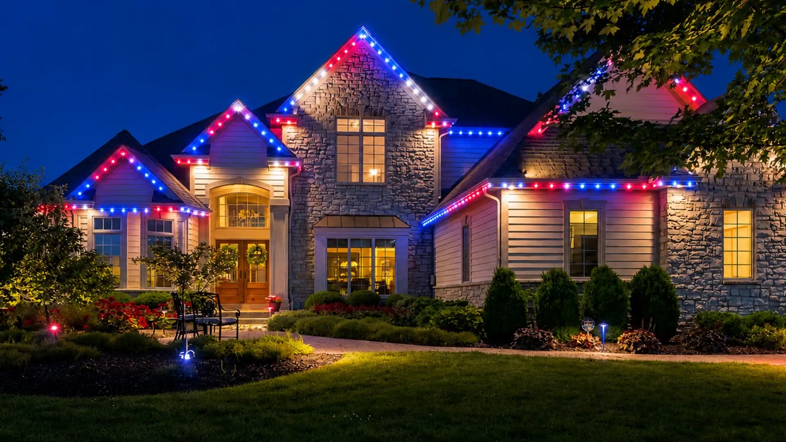 Example of red, white, and blue permanent roofline lights on a two-story home